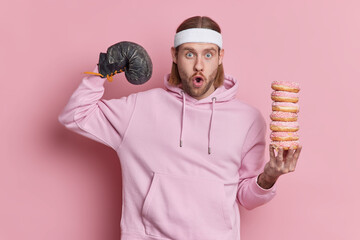 Photo of shocked unshaven man trains in boxing gloves dressed in sportswear leads healthy lifestyle...