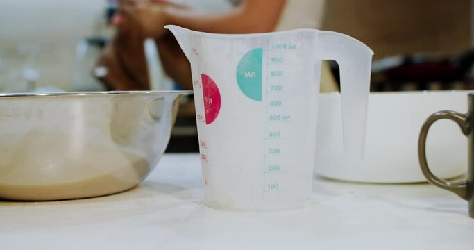 A measuring cup in ml on the kitchen table. Measuring weight of the ingredients