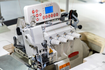 Close-up of details of modern white electric sewing machine on a table in factory. Work place of seamstress. No People.