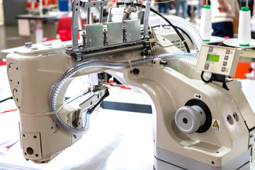 Close-up of details of modern white electric sewing machine on a table in factory. Work place of seamstress. No People.