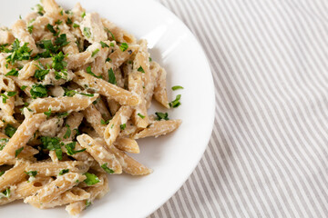 Homemade Chicken Alfredo Penne with Parsley on a white plate, low angle view. Copy space.