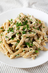 Homemade Chicken Alfredo Penne with Parsley on a white plate, low angle view. Close-up.