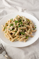 Homemade Chicken Alfredo Penne with Parsley on a white plate, side view. Close-up.