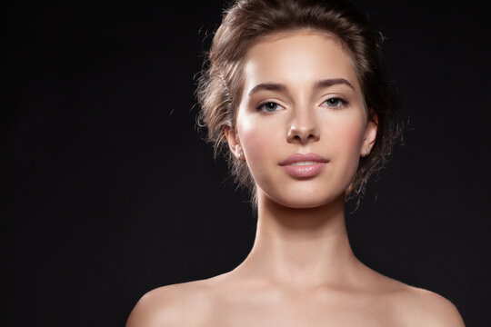 Beautiful young  woman on black studio background with healthy clean hydrated skin face look at camera.