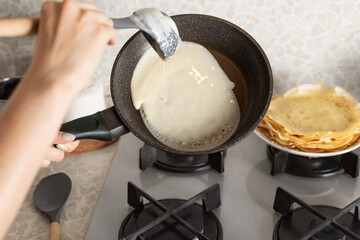 female hands cooking thin pancakes on frying pan in kitchen. Homemade pancakes, crepes for delicious breakfast. close-up. selective focus