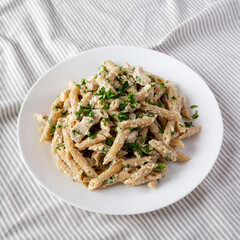 Homemade Chicken Alfredo Penne with Parsley on a white plate, side view.