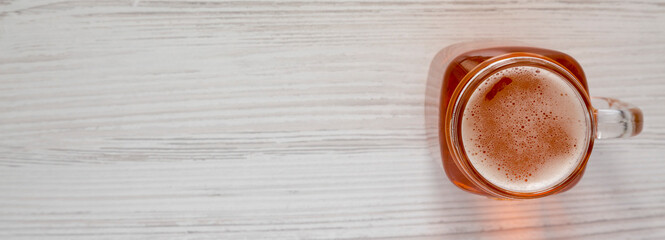 Hard Apple Cider Ale in a Glass Jar Mug on a white wooden table, top view. Flat lay, overhead, from above. Space for text.