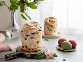 Easter cake Cruffin sweet bread kulich with raisins and painted eggs on window background. Easter holidays breakfast concept.