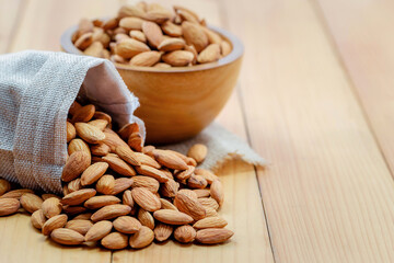 Almonds in brown bowl on wooden background