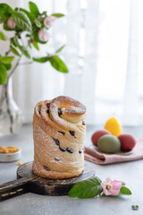 Easter cake Cruffin sprinkled with powdered sugar on wooden board and blossoming branch in the background. Happy Easter concept. vertical image