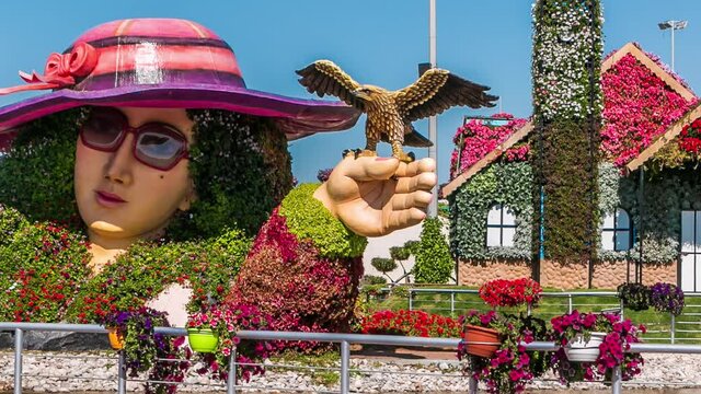 Lake at Dubai miracle garden timelapse with over 45 million flowers in a sunny day, United Arab Emirates. House and sculpture are made from flowers
