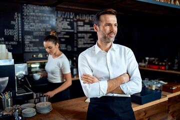 Fototapeta na wymiar Portrait of successful small business owner standing in a cafe looking away