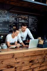 Two restaurant cafe owners working with laptop behind the counter