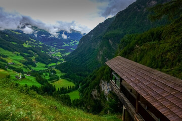 wooden viewing platform in the mountains to a green valley with houses