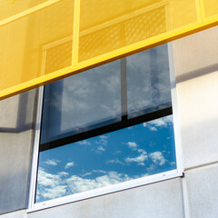 Exterior sun shade and sky reflection in window on office building 