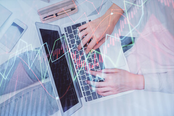 Double exposure of woman hands working on computer and forex graph hologram drawing. Top View. Financial analysis concept.