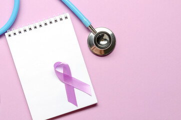Notebook with purple awareness ribbon on a purple background. Copy space. World epilepsy awareness
