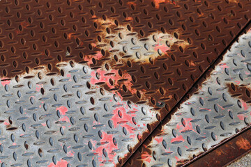 Old corroded and oxidized rusty textured metal plate in a closeup. Brown, red and silver colored surface. Rough industrial background. Interesting geometric texture details. Color image.