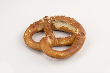 Eine knusprig braune Brezel mit grobem Salz (Laugengebäck) liegt auf einem neutralen weißen Hintergrund
