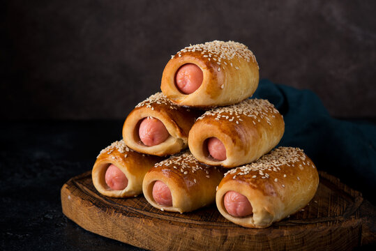 Homemade sausages baked in dough ( pigs in blankets) on a dark background, fast street food