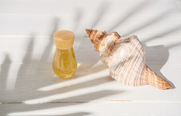summer cosmetic serum next to seashell. moisturising fluid for dry skin and after sun care. vacation skincare, tropical palm leaves shadow. anti wrinkle protection cream. 