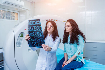 Radiologist with a female patient examining a CT scan