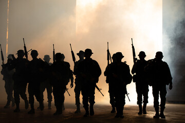 Silhouettes of army soldiers in the fog against a sunset, marines team in action, surrounded fire...