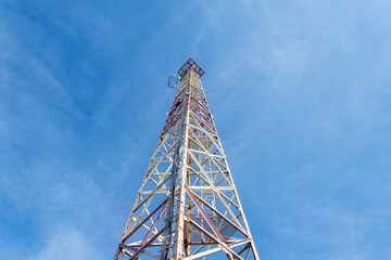 Metal tower for mobile communications, against the blue sky. Bottom view.