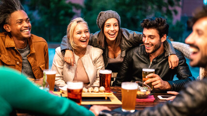 Happy friends drinking beer at brewery bar dehor - Friendship lifestyle concept with young milenial people enjoying time together at open air pub - Warm color tones on vivid filter with focus on girls - 411456067