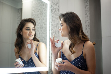 Young woman near the mirror, skin care morning routine