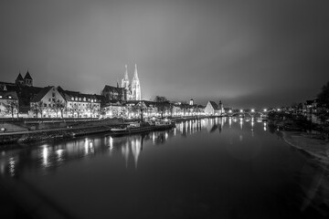 Blick zu der steinerne Brücke in Regensburg nachts im Nebel über den Fluss Donau mit dem beleuchteten Dom und historischer Altstadt , Deutschland