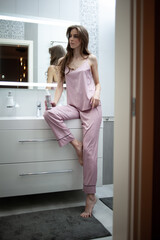 Natural beauty and haircare concept. Charming woman in bathrobe looking at mirror in bathroom, touching fresh healthy hair and smiling wide after spa procedure at home