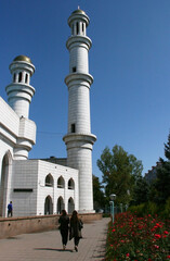 Fototapeta na wymiar Almaty, Kazakhstan - May 2018: The modern mosque with golden domes in front of mountains in good weather in the green city.