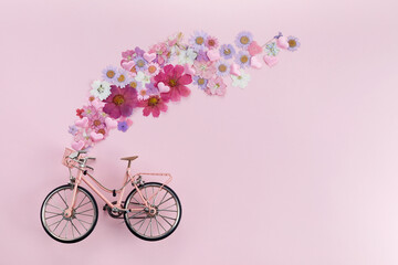 Fototapeta na wymiar Flowers fly out from pink bicycle bascet on pink background. Romanitic concept for Valentine day, women or mother day.