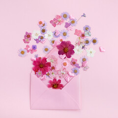 Envelop with wild colorful flowers on pink background. Love concept. Flat lay.