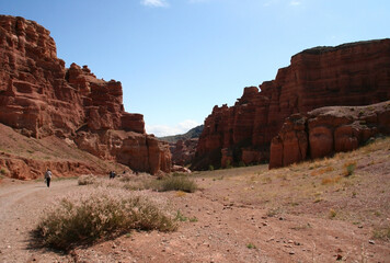 Fototapeta premium Charyn Canyon in South East Kazakhstan, summer 2019. Trail in red rock canyon desert. Red rock canyon desert trail landscape. Yellow-red rocks in Kazakhstan.