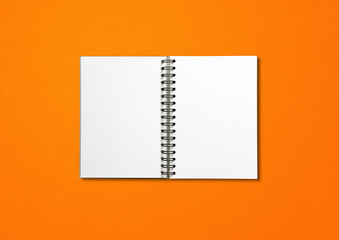 Blank open spiral notebook isolated on orange