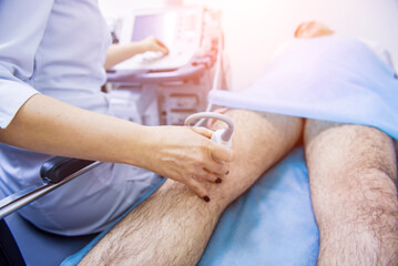 Obraz na płótnie Canvas Doctor using ultrasound scanning machine examining injured knee