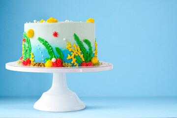 Cake in the form of an underwater sea multicolored world with algae and coral on a blue background.