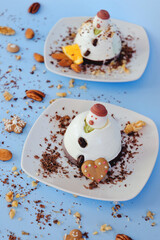 Ice cream background in the shape of two edible snowmen on white plates close up. Top view. Creative idea for Christmas and New Year festive desserts. Funny food idea for kids.