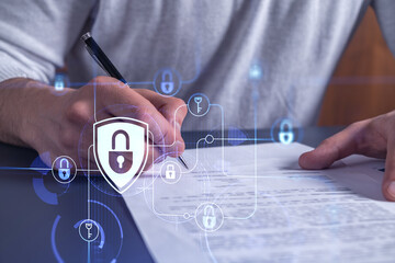 A businessman in casual wear signing the contract to prevent probability of risks in cyber security. Padlock Hologram icons over the working desk.
