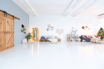 large very bright spacious stylish open plan Bali style apartment with hanging bed and panoramic windows. white floor and walls, simple wooden furniture. decorated with a christmas tree