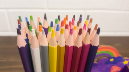 A set of colored pencils, stationery. A lot of multicolored pencils on the table.
