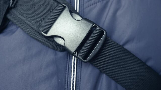 Woman is fastening the strap of a backpack with a fastex buckle. Secure, comfortable backpack latch.