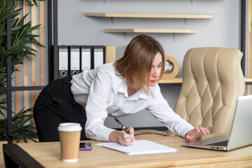 Attractive female secretary working in bending over the desktop instead of the boss. She is nervous...