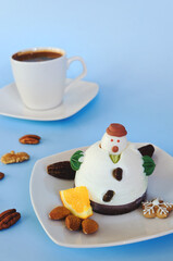 Ice cream in the shape of edible snowman on white plate and coffee cup close up. Top view. Creative idea for Christmas and New Year festive desserts. Funny food idea for kids.