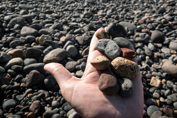 Picking up stones from a pebble beach in calm natural light