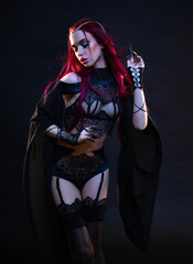 Redhead vampire woman posing on black background in lace lingerie and heels