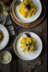 Rustic dinner with risotto all Milanese. Risotto with Saffron and parmesan on white plate on wooden table. 