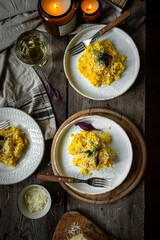 Rustic dinner with risotto all Milanese. Risotto with Saffron and parmesan on white plate on wooden table. 
